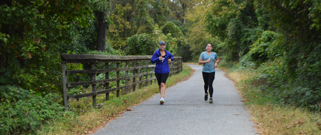 Two women run on an outdoor path